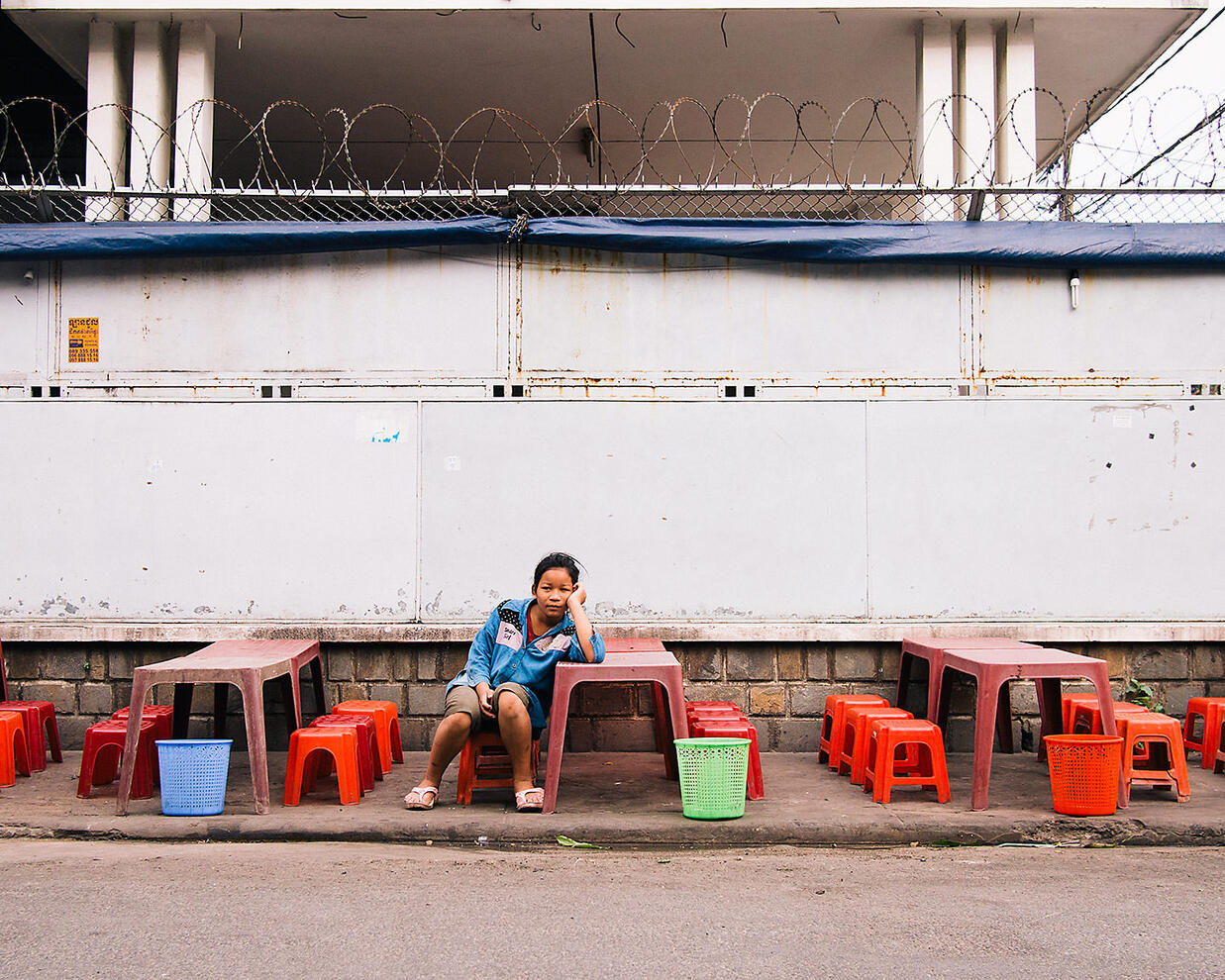 A young girl waits for the customers arrive at her family's roadside restaurant - Phnom Penh, Cambodia